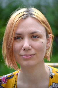 a photo of rebecca bourke psychotherapist. She is a white woman in her late 30s with bleached blonde hair and dark roots showing. She is smiling